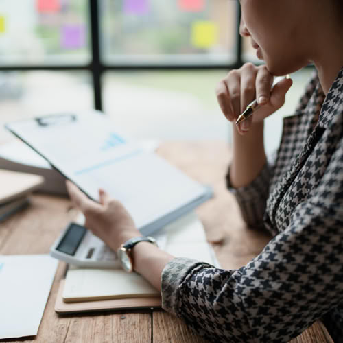 Business professional reviewing a chart on a clipboard at a desk.